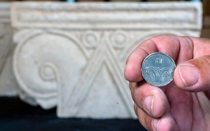 A five-shekel coin juxtaposed with a column head found at Armon HaNatziv. Image credit: Yaniv Berman, Israel Antiquities Authority